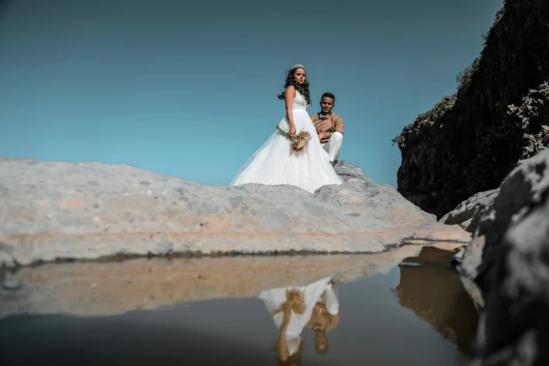 a couple standing on the edge of a cliff looking at soing in the water