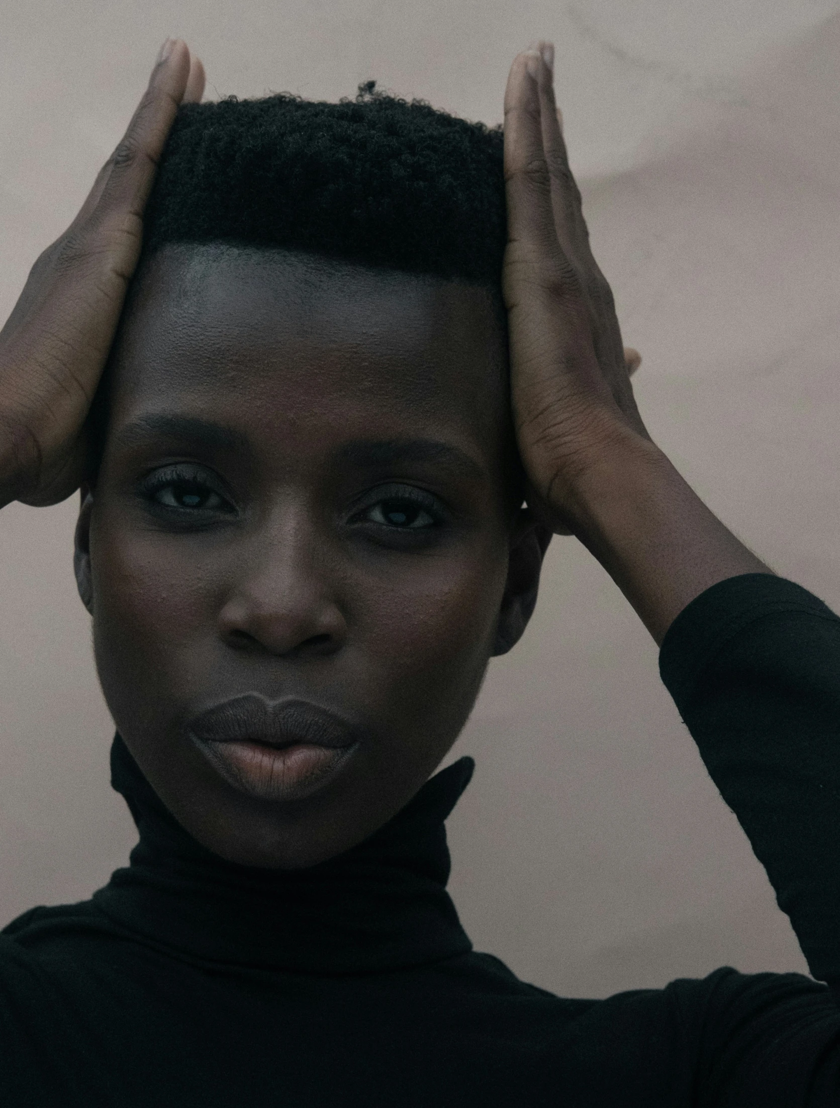 a woman wearing black has her hands in her hair