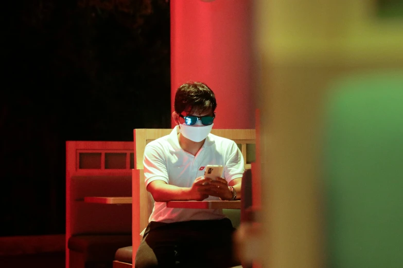 a young man wearing a mask sitting on a chair