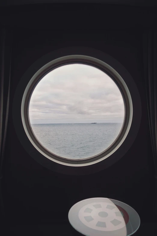 a round window is showing the ocean and an object on the floor