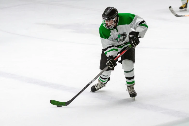 a person with green and white uniform playing ice hockey