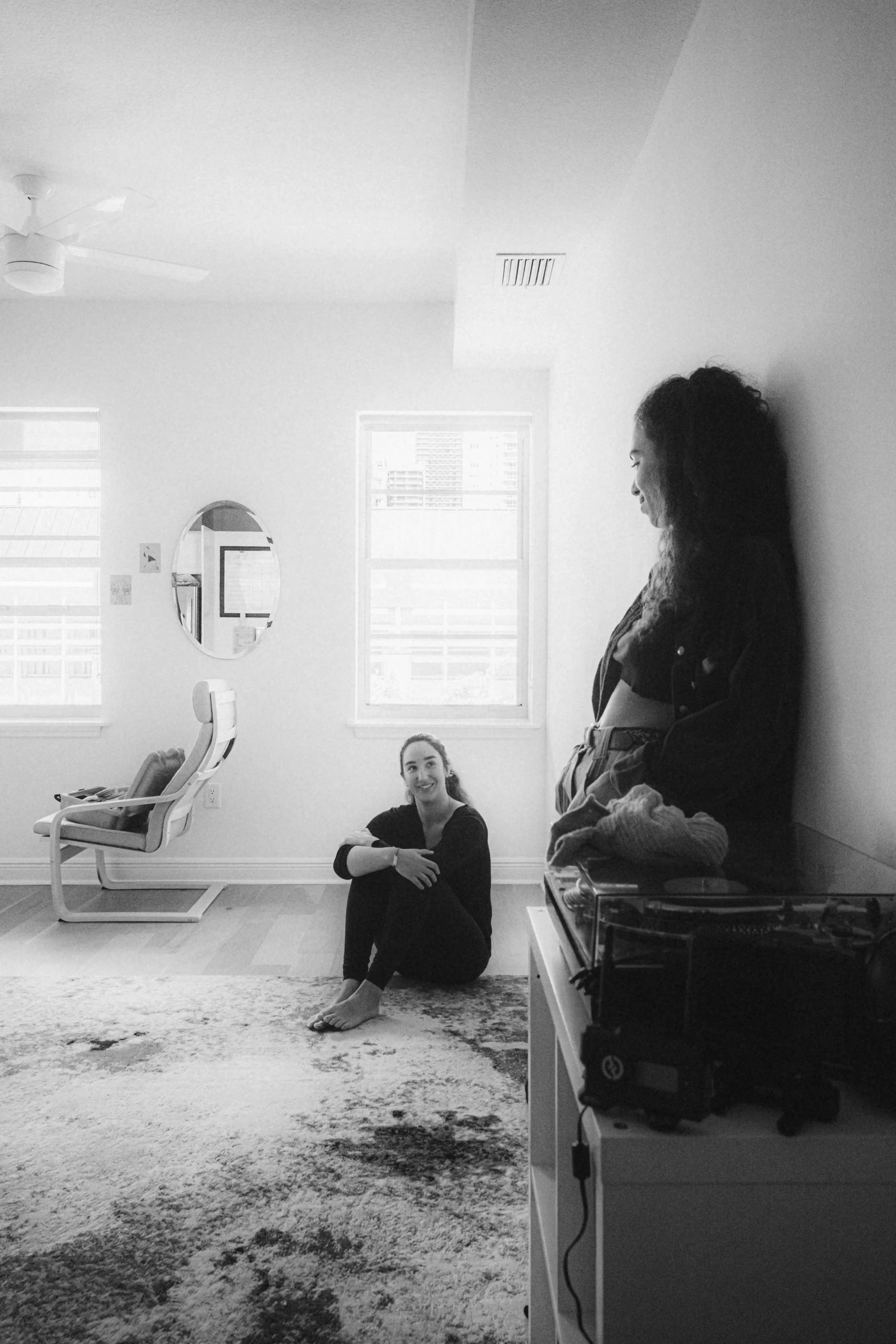 two women sit in a living room with their legs crossed