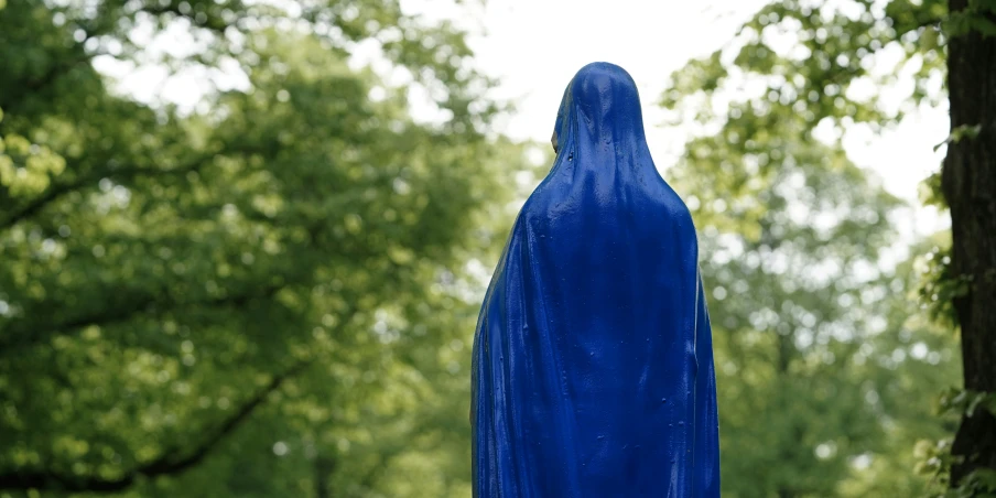 a blue sculpture is in front of a tree