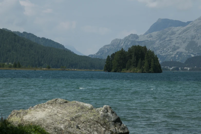 two people are sitting on a rock near the water