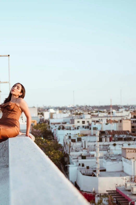 the girl in brown is posing at top of a roof