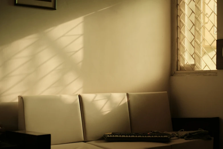 a white couch sitting in front of a window under a sunlit shade