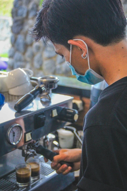 a man is filling cups into his coffee machine