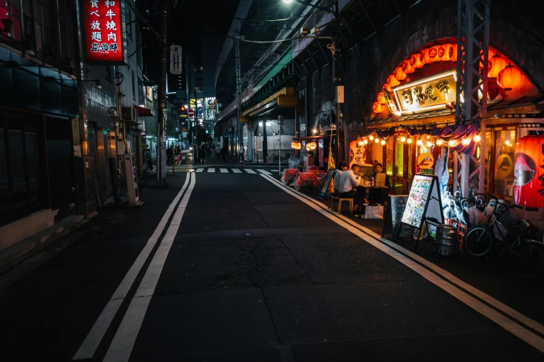 a narrow street in the middle of town lit up at night