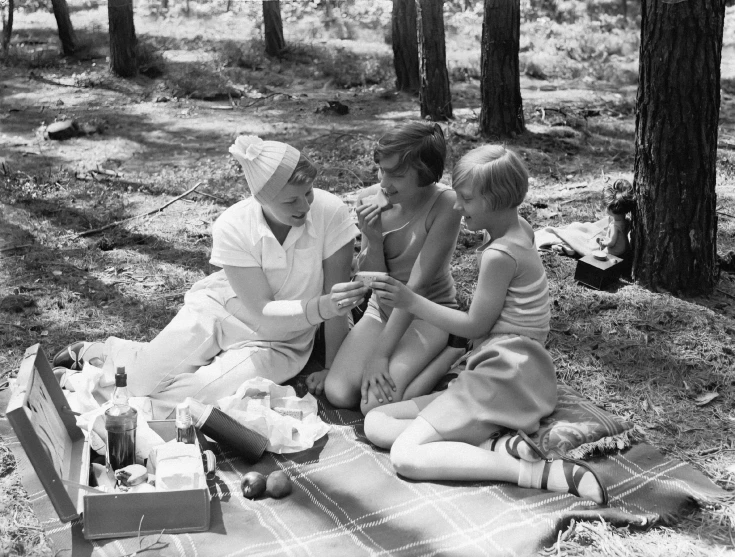 a group of three people sitting on top of a blanket