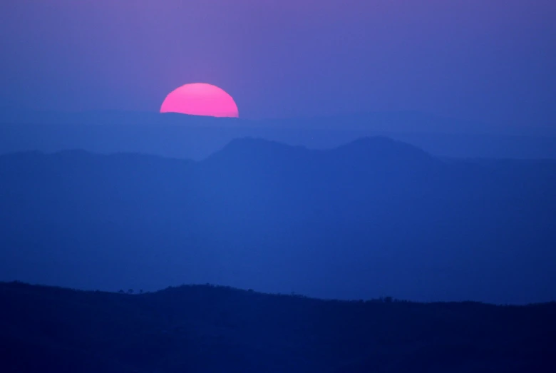 the sun is setting over the mountains in this image