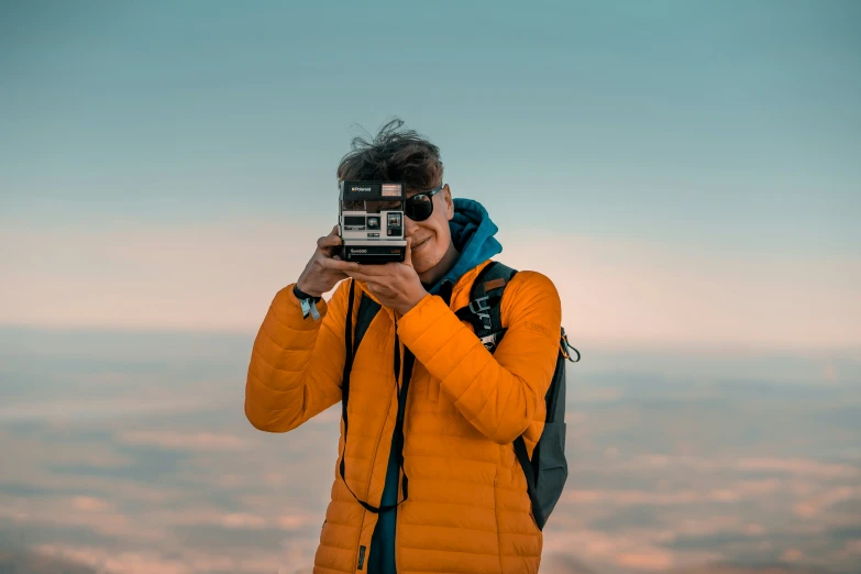 someone wearing a yellow coat takes a po on top of the mountain