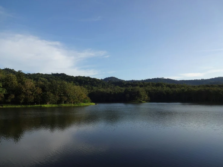 the lake is surrounded by green trees and hills