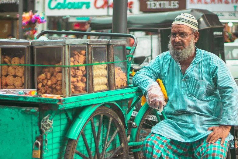 an old man sits in front of an orange cart