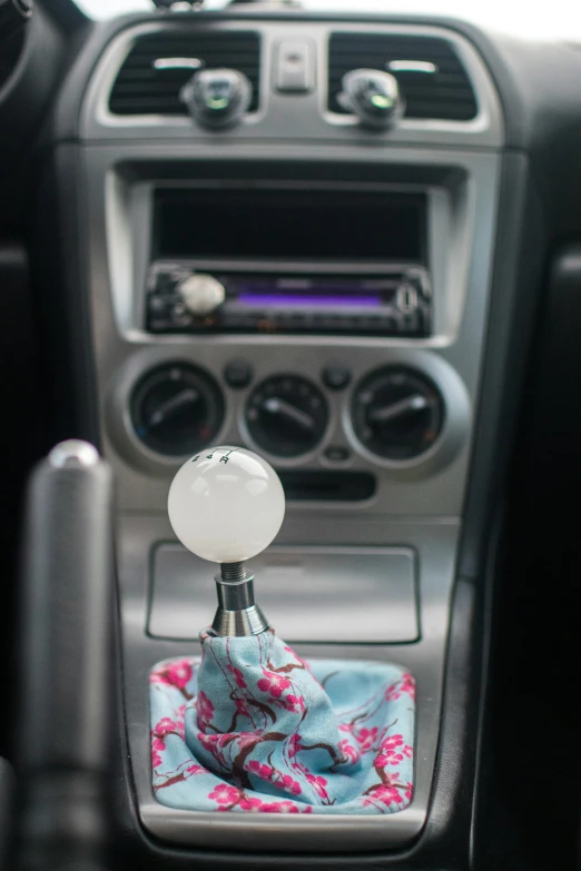 the interior of a car, with an automatic cup holder and colorful fabric blanket on the dash of the vehicle