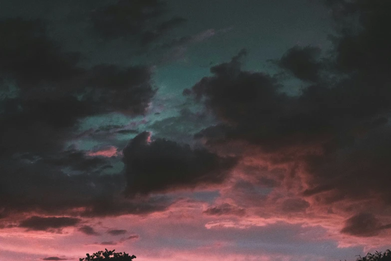 a cloudy sunset with a lone tree and a single building