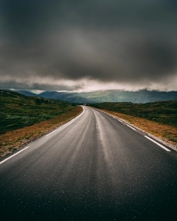 a single road goes straight to the horizon under storm clouds