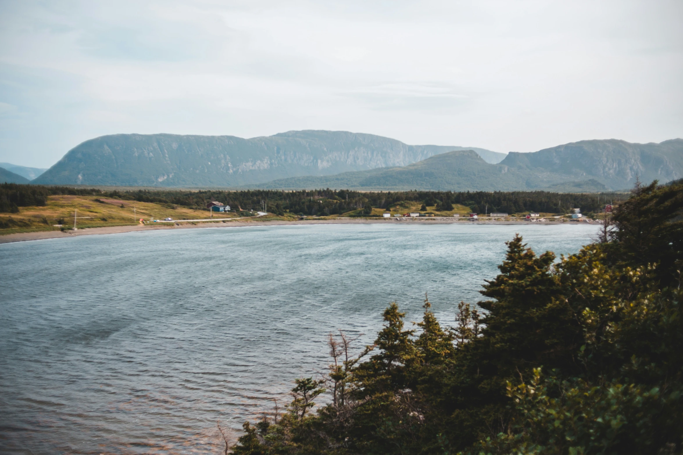 a body of water surrounded by mountains on a sunny day