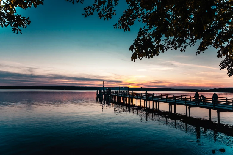 people sitting on a pier during the sun set