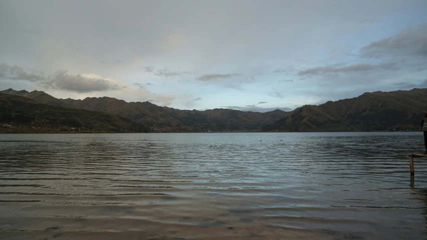 man wading in large lake on a gloomy day