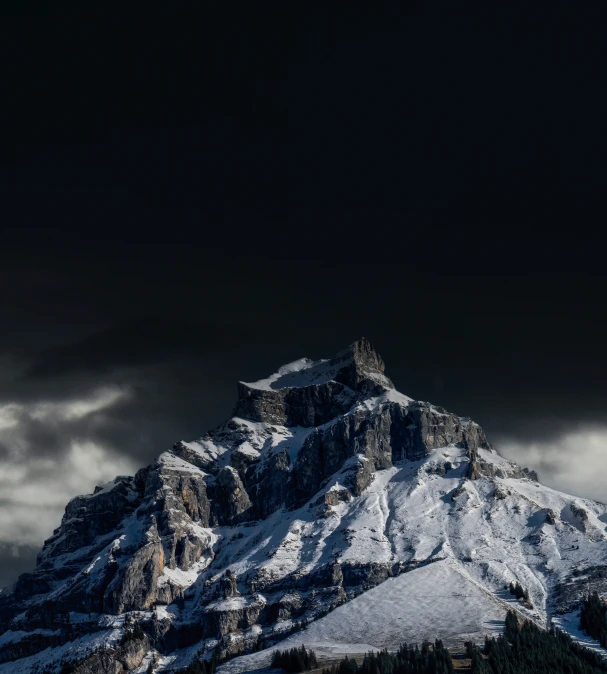 a mountain with snow covered mountains and dark skies