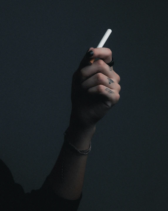 a hand holding a cigarette with a small white cigarette lighter sticking out