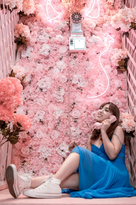 girl in a blue dress sitting by the flowers on the wall