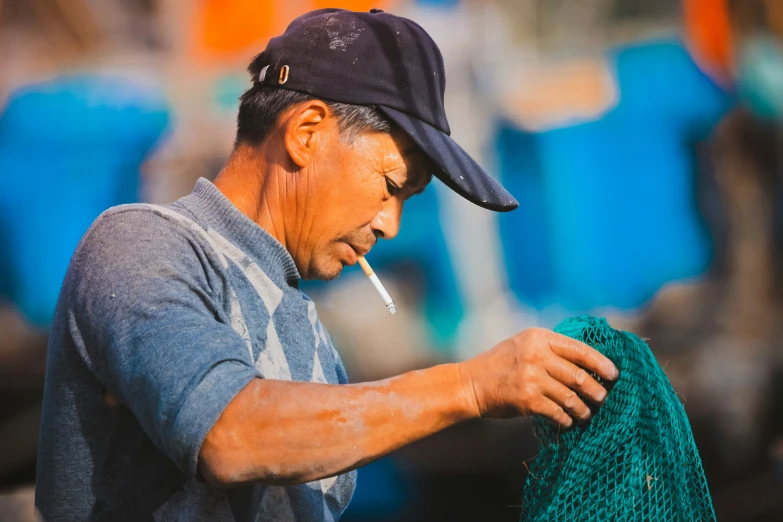 a man is standing and working with a green mesh on a fishing net