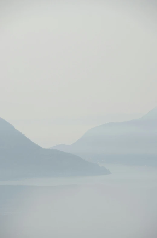 birds are flying over some foggy water