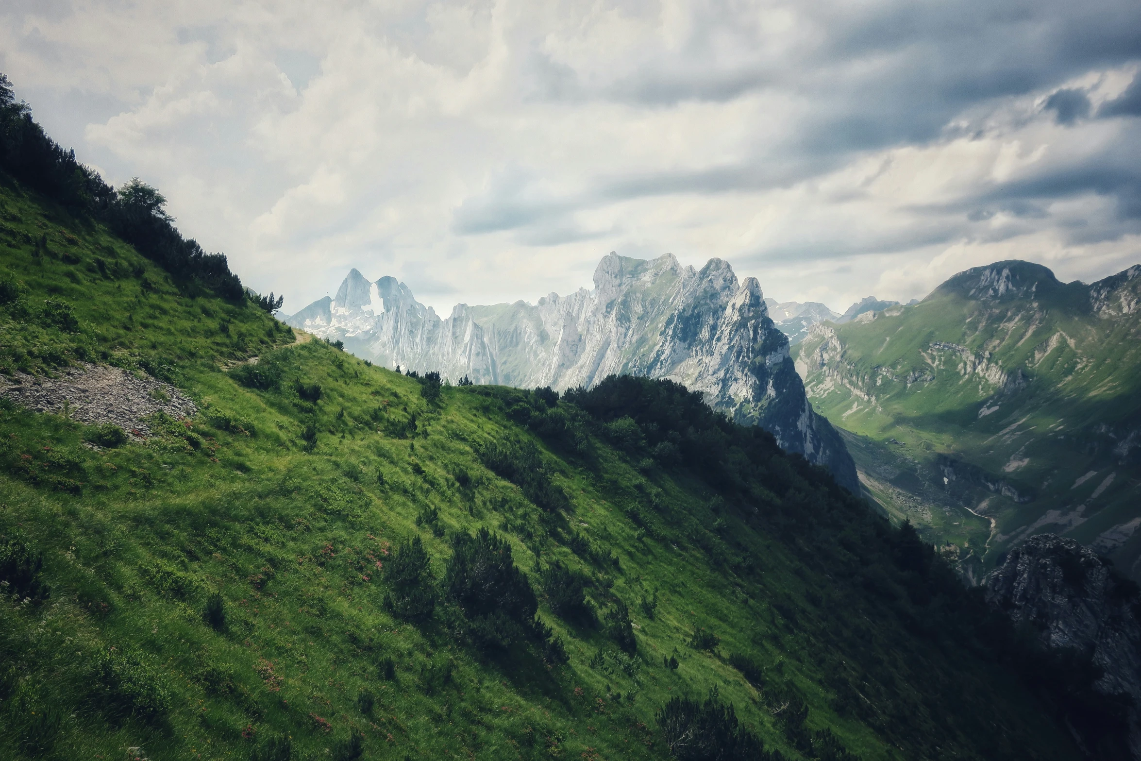 the tops of some very steep mountain ranges with a cloudy sky