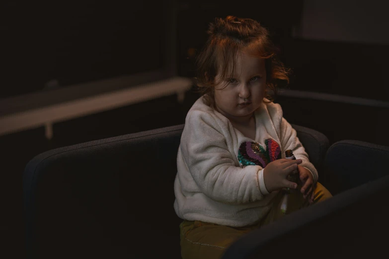 a child is sitting on the sofa and holding a flower