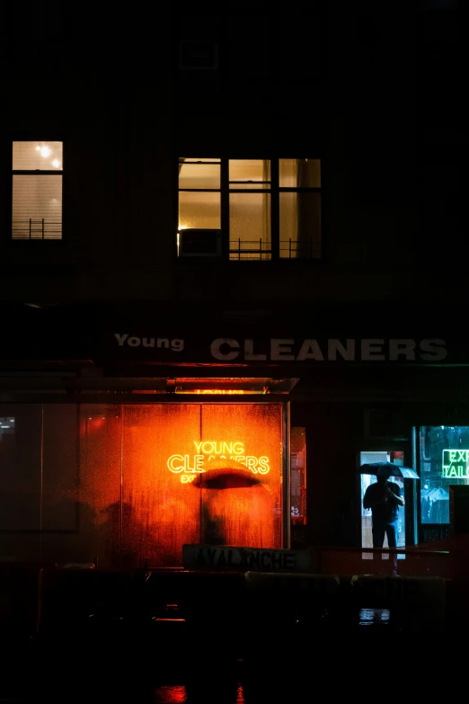 a man standing outside the entrance of a business at night