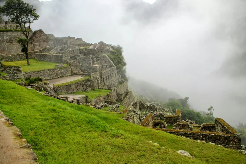 several large ruins on the side of a mountain with green grass