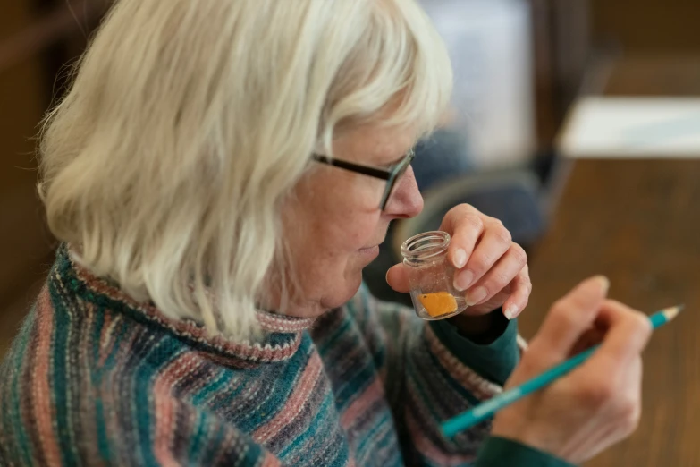 an older woman with white hair and glasses holding up an object