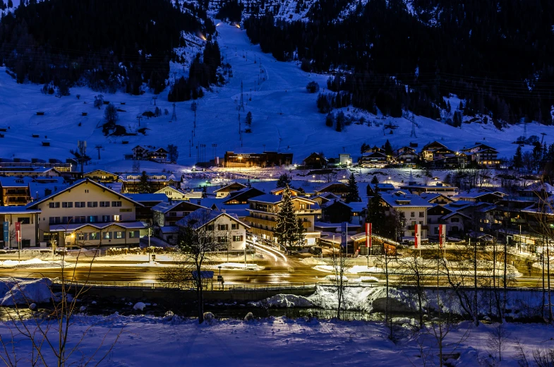 a town lit up with lights at night in the snow