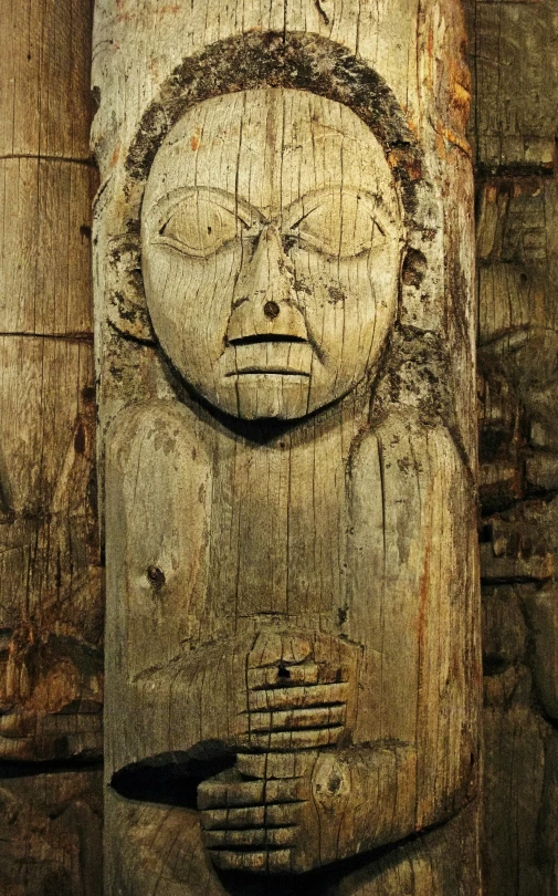 a wooden carved face with two hands on it