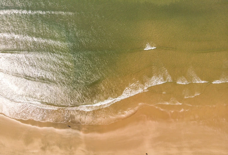 top view of ocean waves with sunbeams and shore line