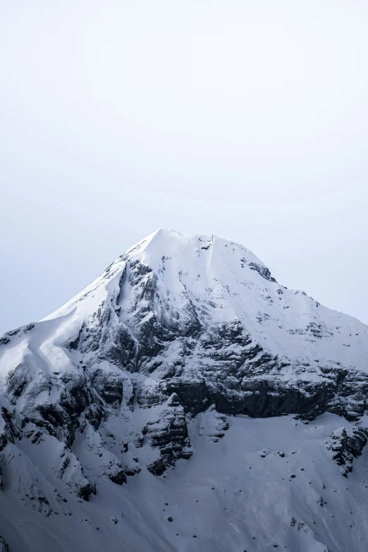 the top of a snow covered mountain with snow falling