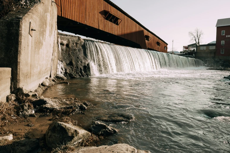 a bridge over a small river that has a waterfall going underneath it