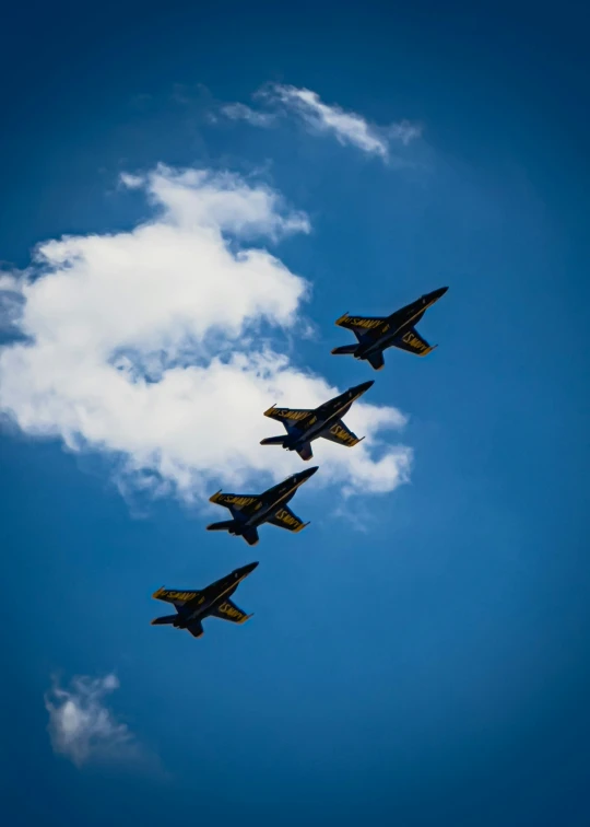 four fighter jets are flying side by side in the sky