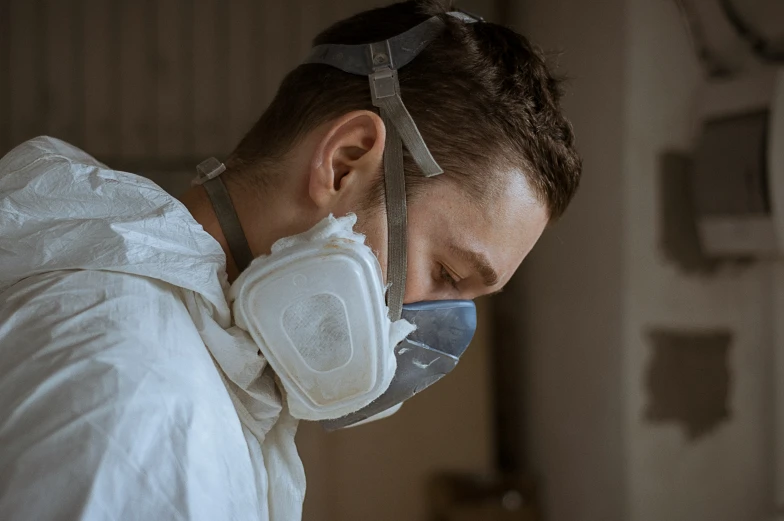 a man wearing a white protective suit has a face mask on