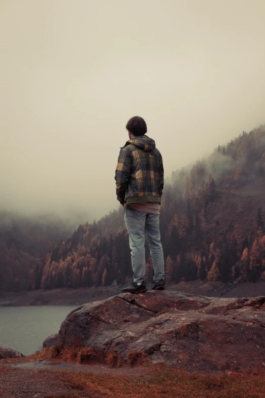 a man standing on top of a rock next to a forest