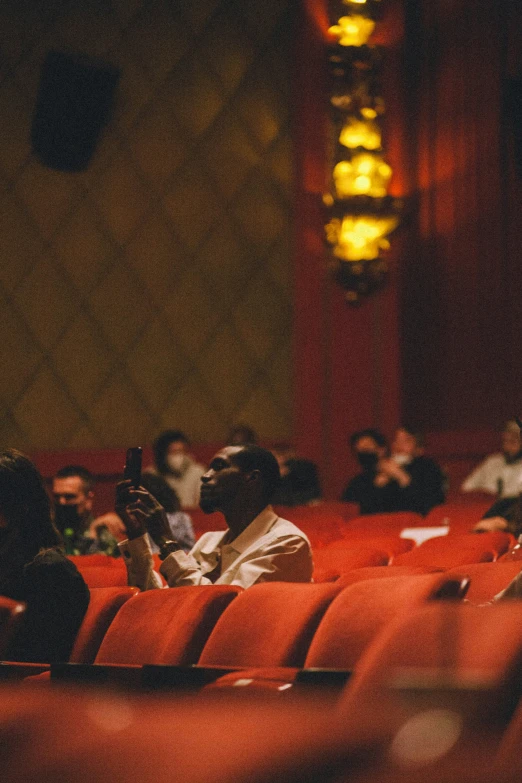 people are seated in an auditorium and people in the background