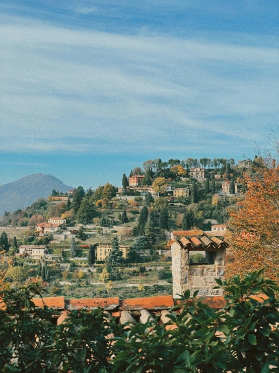 the houses on a hill in autumn with trees around them