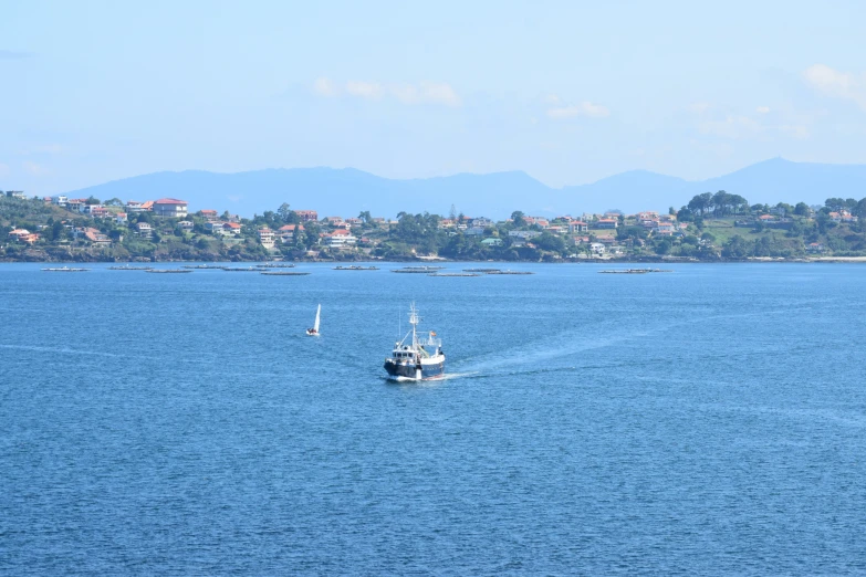 a boat sailing on the ocean surrounded by land and mountains