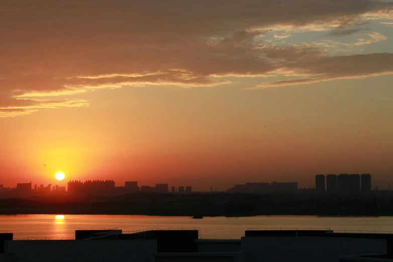 the sun setting over water with city skyline in background