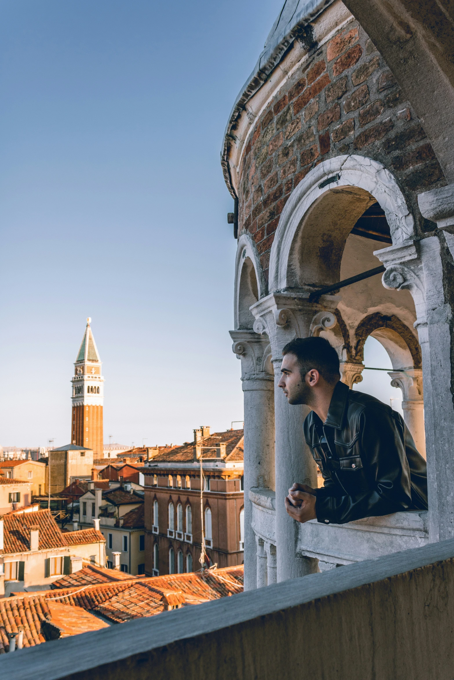 a man looking down at the skyline from a balcony