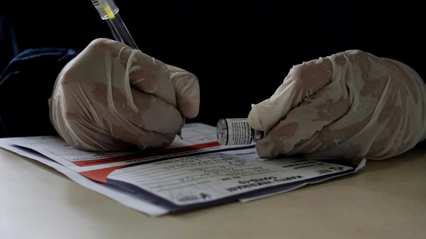 a person with gloves writing soing on paper