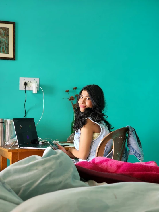 a woman sitting on a chair while using her laptop