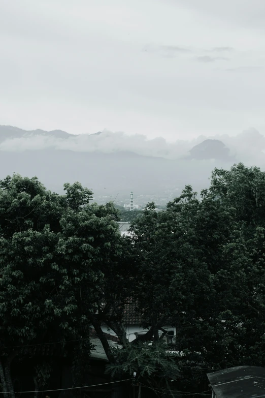 an overcast day in a city park with benches and benches, and hills in the background