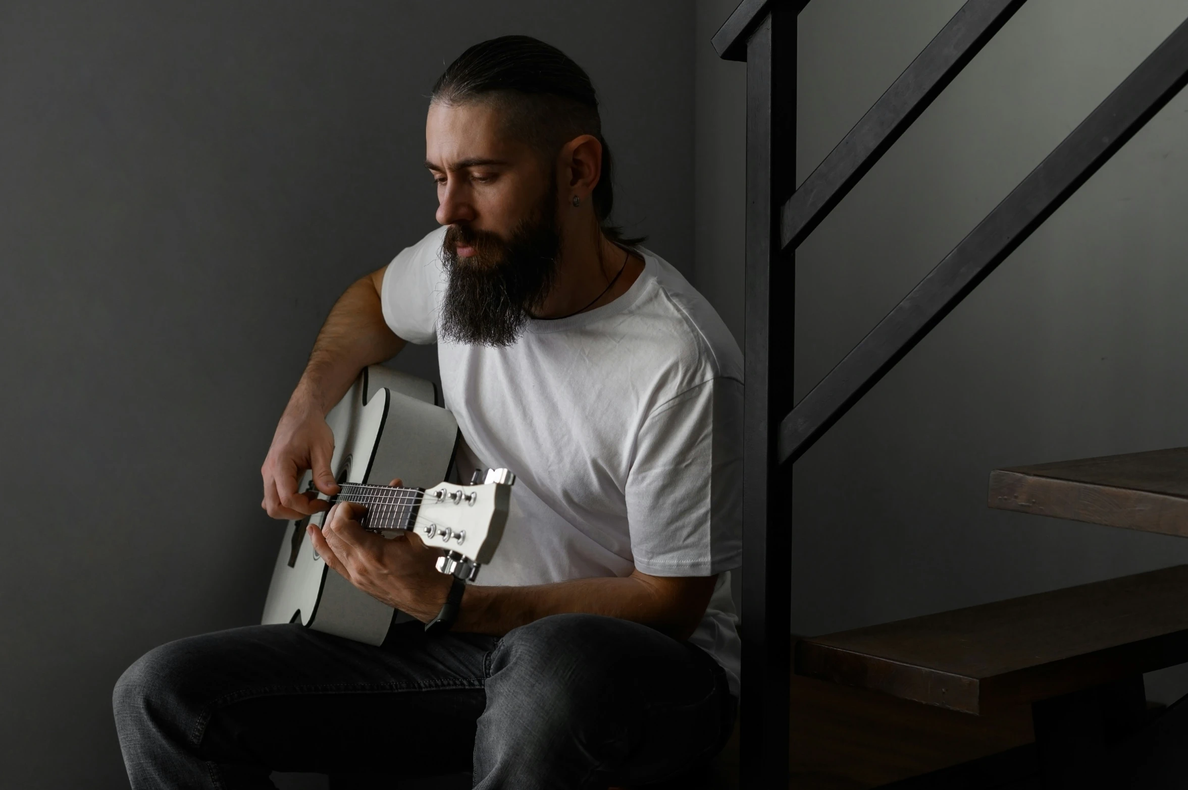 the man is playing a guitar while sitting on a set of stairs